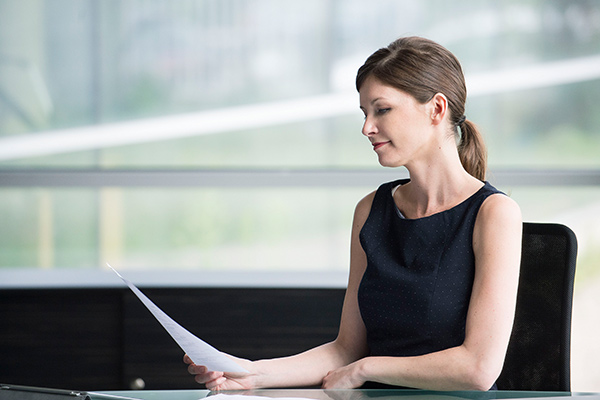 Frau liest Dokument am Tisch